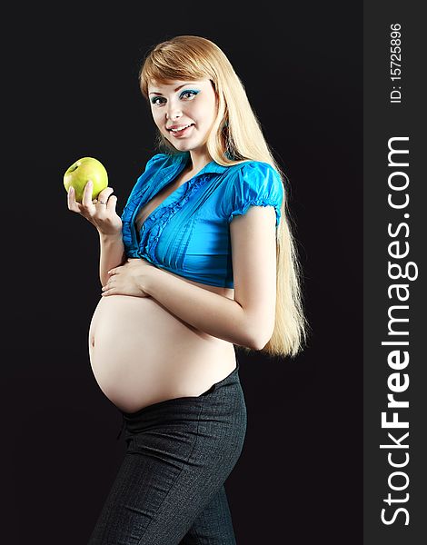 Portrait of a beautiful pregnant woman eating fresh apple. Over black background. Portrait of a beautiful pregnant woman eating fresh apple. Over black background.