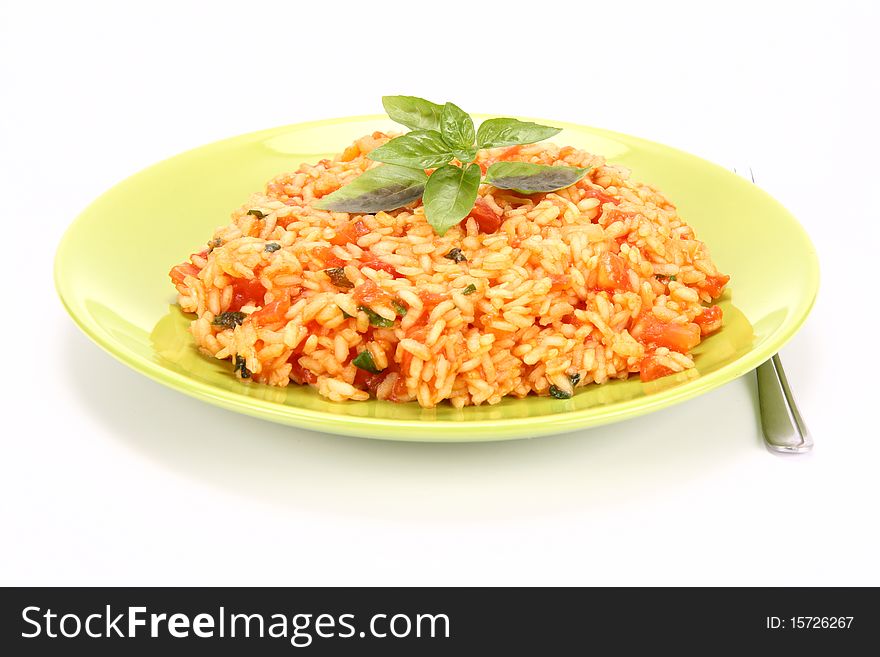 Risotto with tomatoes on a green plate decorated with basil