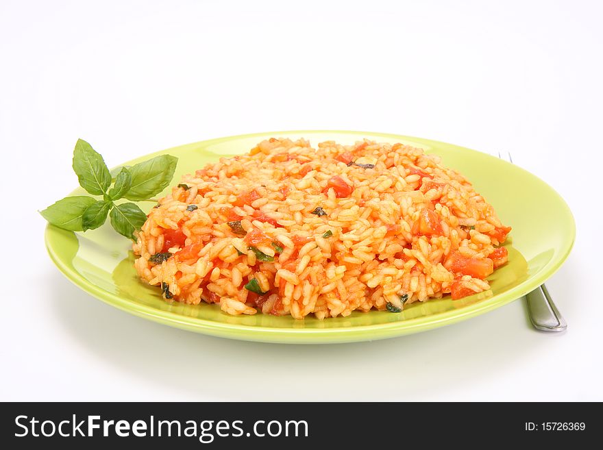 Risotto with tomatoes on a green plate decorated with basil