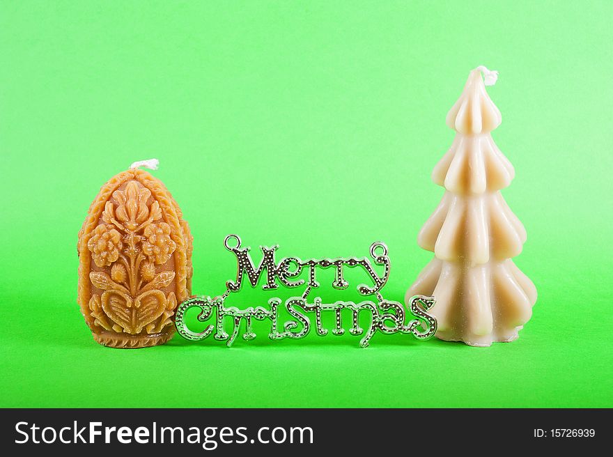 Silver merry christamas sign with two christmas candles isolated on green. Silver merry christamas sign with two christmas candles isolated on green