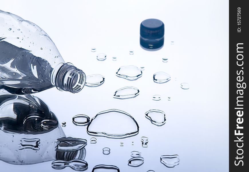 The photo shows a lying plastic bottle and some water drops on a mirror