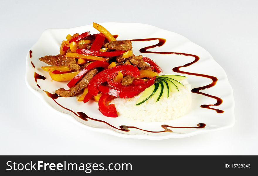 Grilled meat pieces with paprica and rice garnish isolated on a white plate. Grilled meat pieces with paprica and rice garnish isolated on a white plate