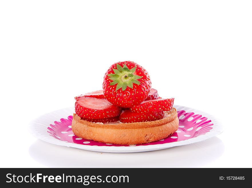 A biscuit with strawberries on a pink dotted plate, isolated over white