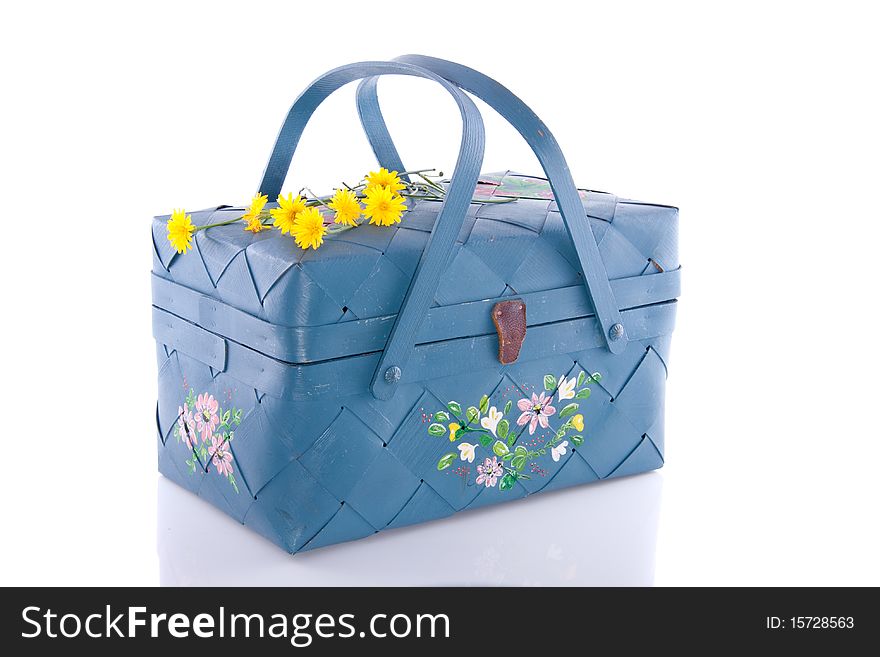 A blue wicker basket decorated with yellow daisies isolated over white background
