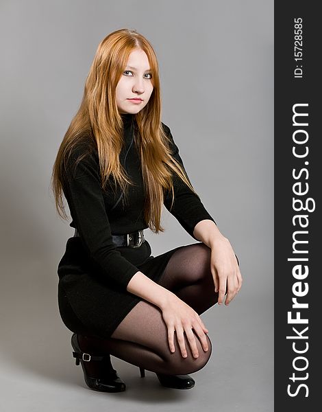 Young attractive girl in a black dress on a gray background. Young attractive girl in a black dress on a gray background