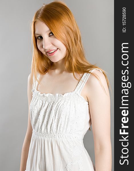 Young attractive girl in a white dress on a gray background. Young attractive girl in a white dress on a gray background