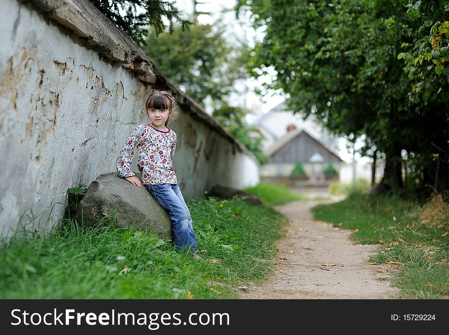 Nice toddler girl sitting near the wall of catholic church on countre road in Belarus. Nice toddler girl sitting near the wall of catholic church on countre road in Belarus