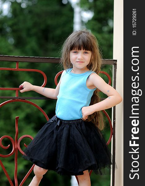 Adorable toddler girl with very long dark hair on the balcony in tutu skirt