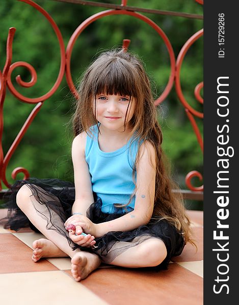 Adorable toddler girl with very long dark hair on the balcony in tutu skirt