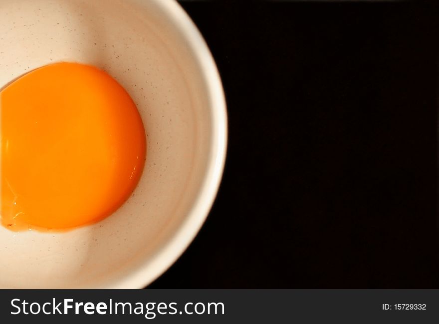 Egg's yolk in white cup on black background. Egg's yolk in white cup on black background.