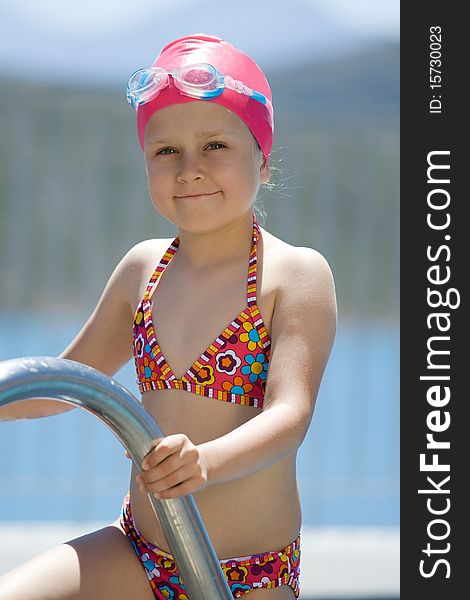 Close-up portrait of smiling cute little child in bathing cap, glasses near swimming pool stairs. Close-up portrait of smiling cute little child in bathing cap, glasses near swimming pool stairs