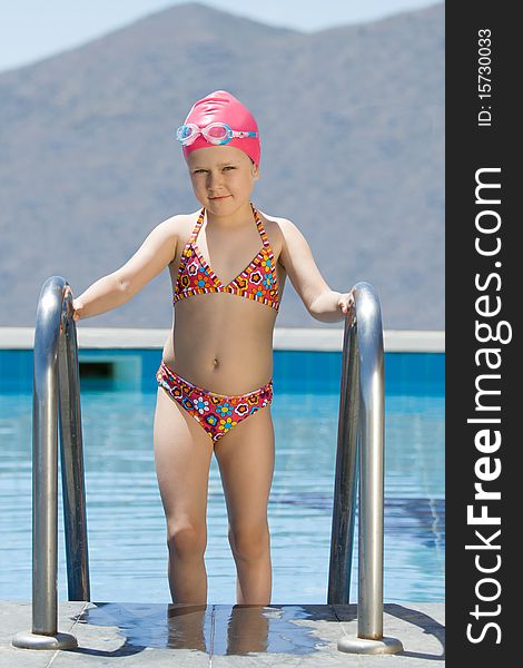 Little girl in bathing cap, glasses walks up stair