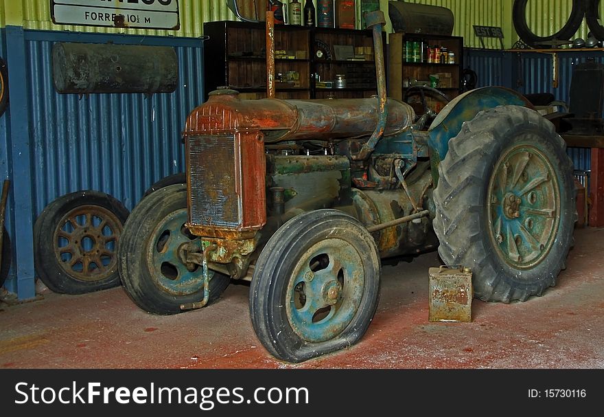 Rusty old tractor sitting in the corner of an old 1930 style garage. Rusty old tractor sitting in the corner of an old 1930 style garage