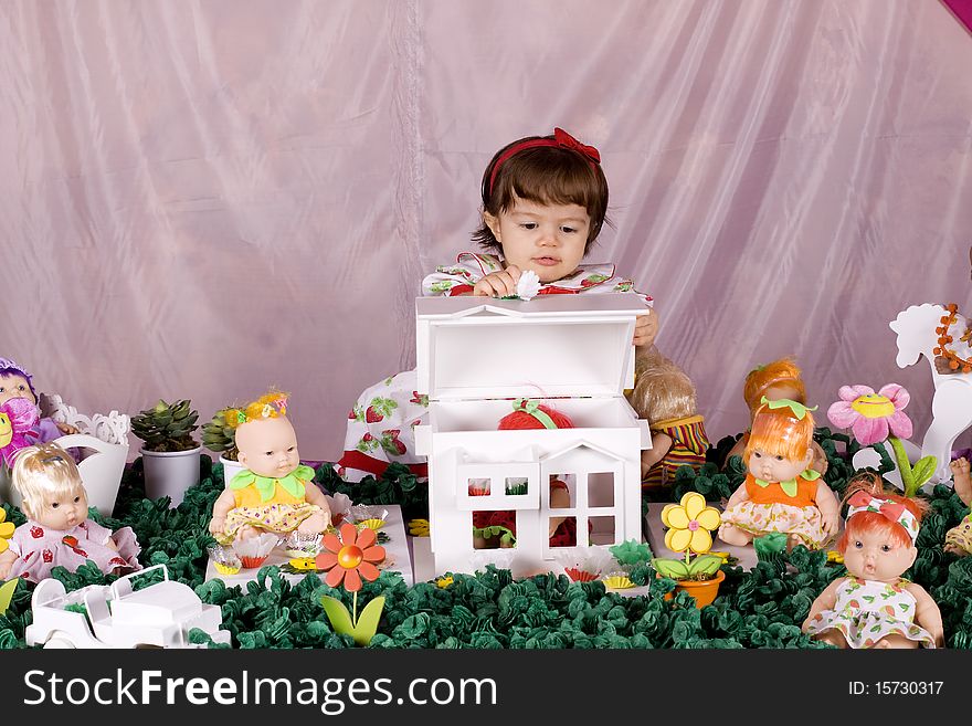 Baby girl opening a doll house and looking indside. Baby girl opening a doll house and looking indside