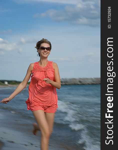 Young woman running on the beach - with a little blur around her legs to enhance the sense of speed