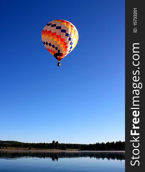 A hot air balloon floats over a calm lake. A hot air balloon floats over a calm lake