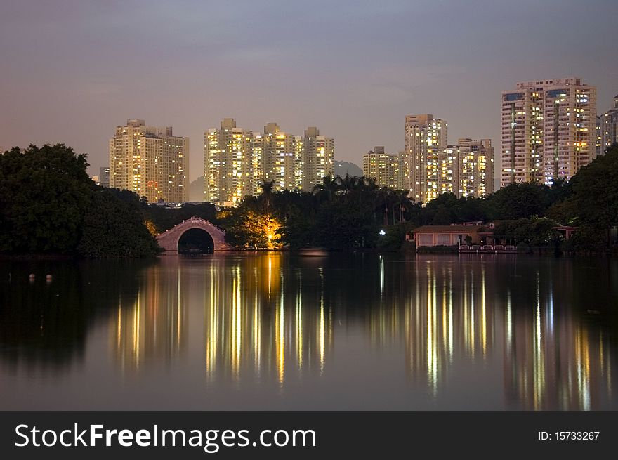 Lake park by night, Leeche Park in Shenzhen city, China. Evening landscape with reflections in water and small bridge.