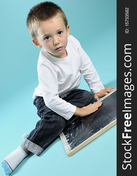 Little Boy Playing With Chalk On Black Board