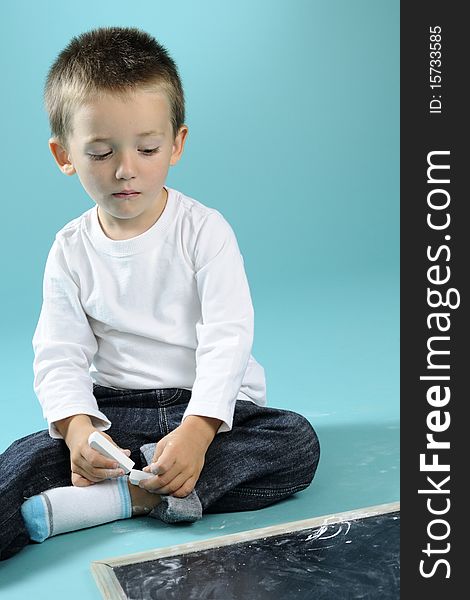 Little Boy Playing With Chalk On Black Board