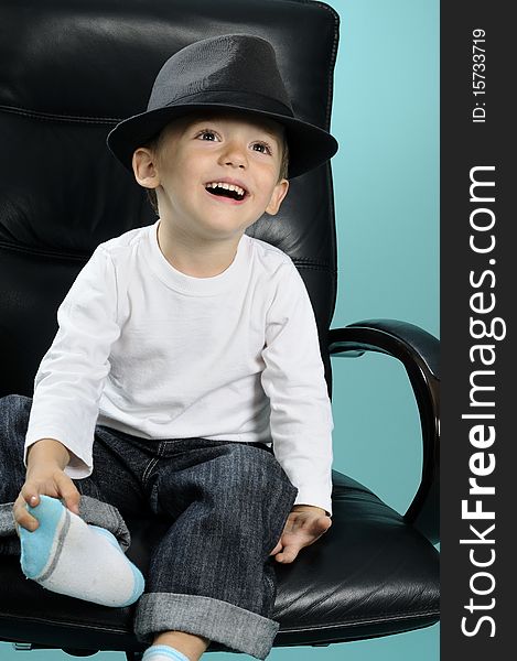 Photo with one child sitting on chair in studio and showing black accessory. Photo with one child sitting on chair in studio and showing black accessory