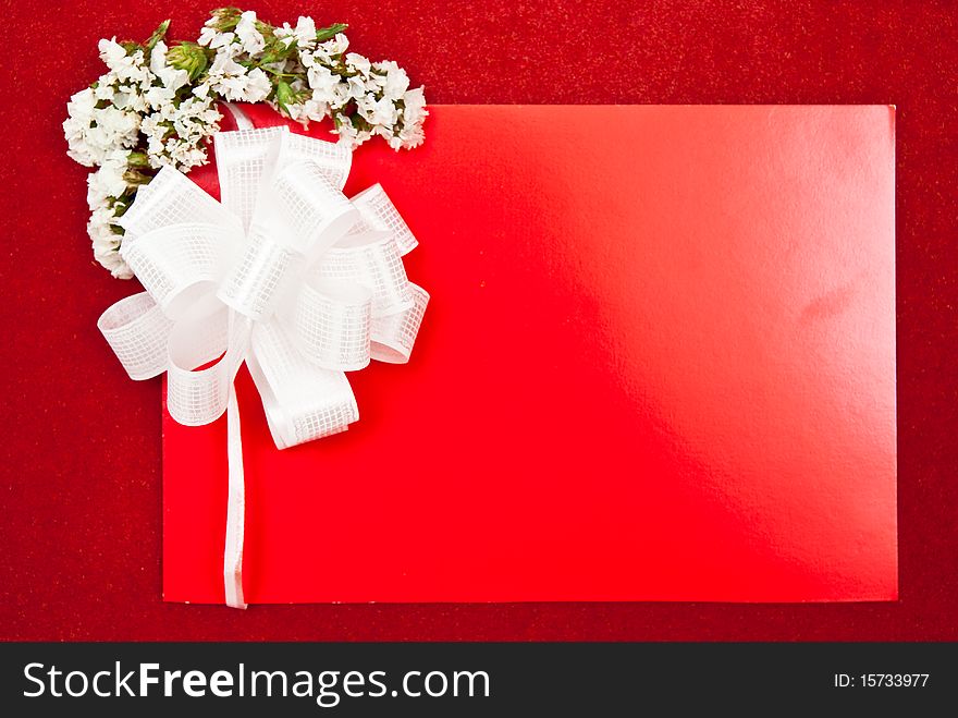 Greeting card with bow and flowers on red background. Focus on bow