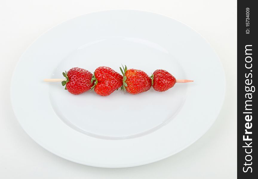 White plate with skewer strawberries. White plate with skewer strawberries
