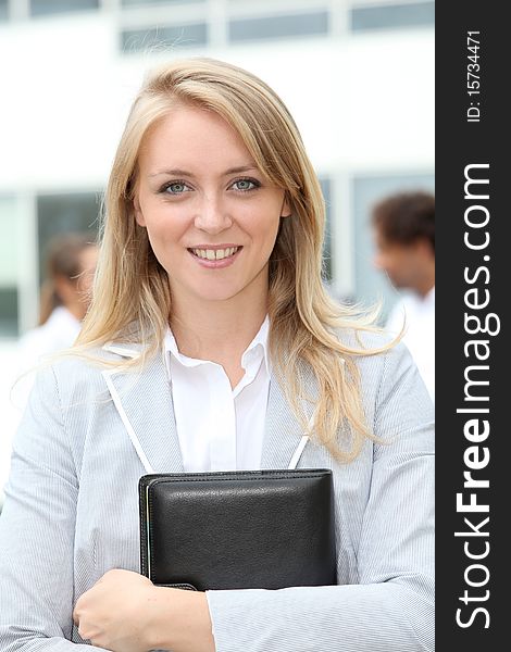 Smiling blond businesswoman holding notebook. Smiling blond businesswoman holding notebook