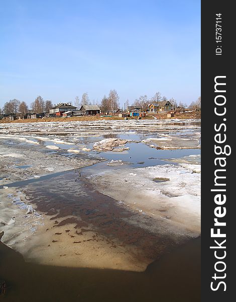 Driving of ice on small river against village