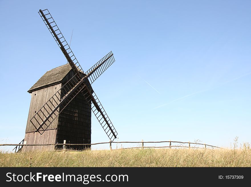 Old windmill (trestle type) in a field with a fence