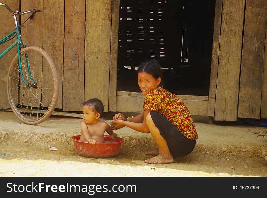 Female Thay giving bath to her child outside her home. Female Thay giving bath to her child outside her home.