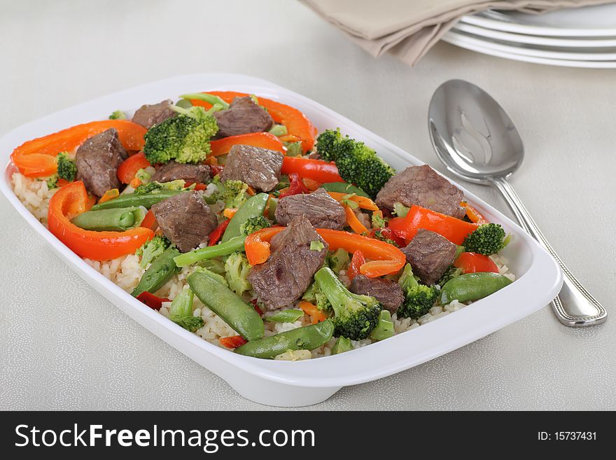 Beef stir fry with broccoli, red peppers and pea pods over rice