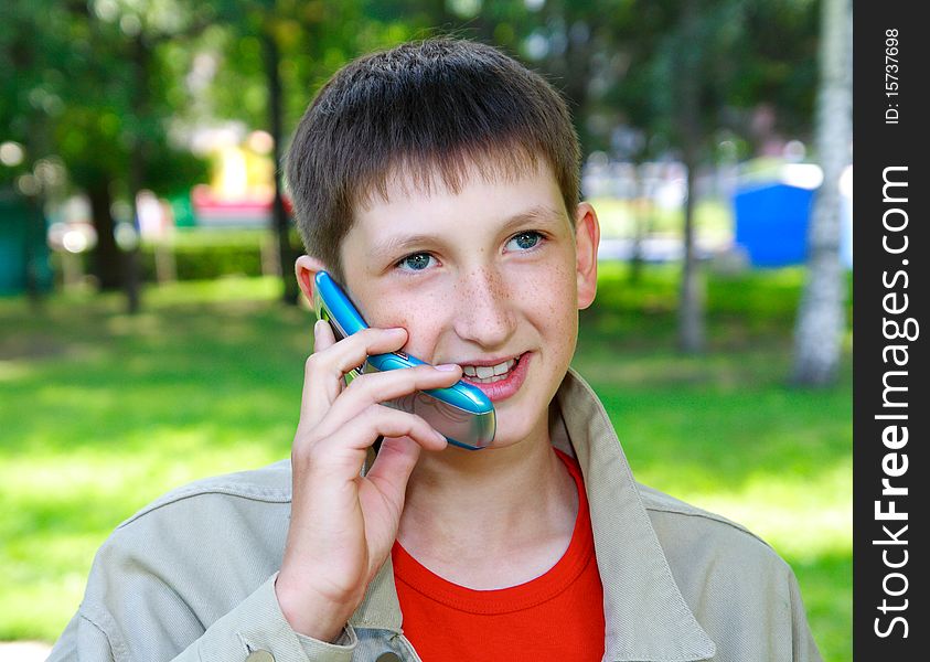 Young boy speaks by phone outdoors. Young boy speaks by phone outdoors