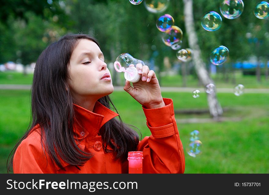 Beautiful girl blowing soap bubbles outdoors