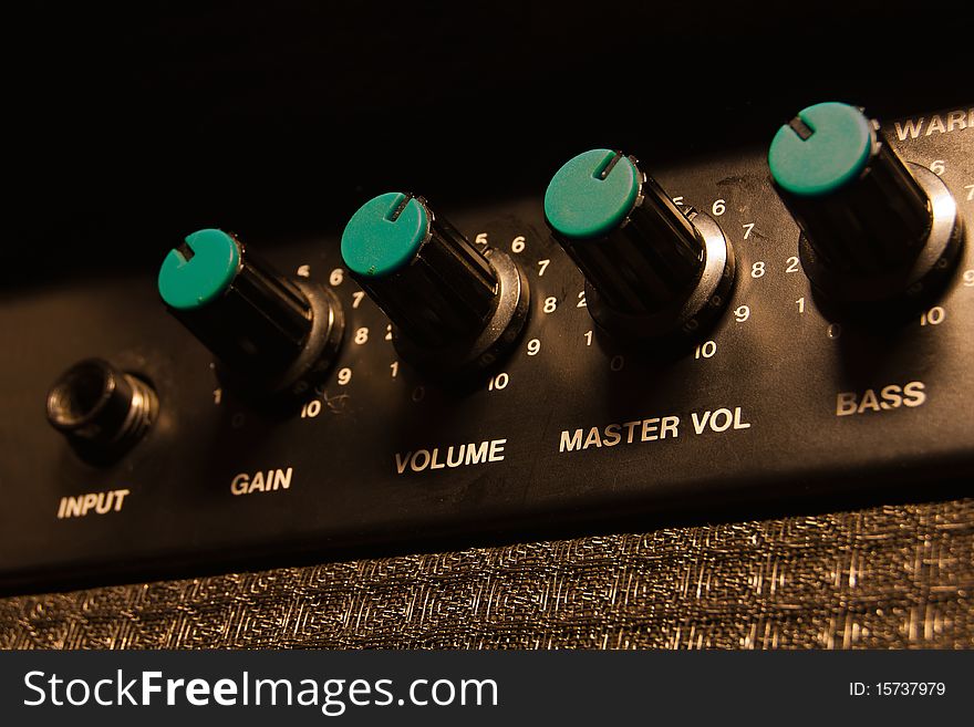 Detail of a worn-out guitar amplifier with blue knobs