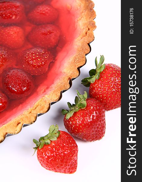 Strawberry Tart in a tart pan and some strawberries on a white background in close up