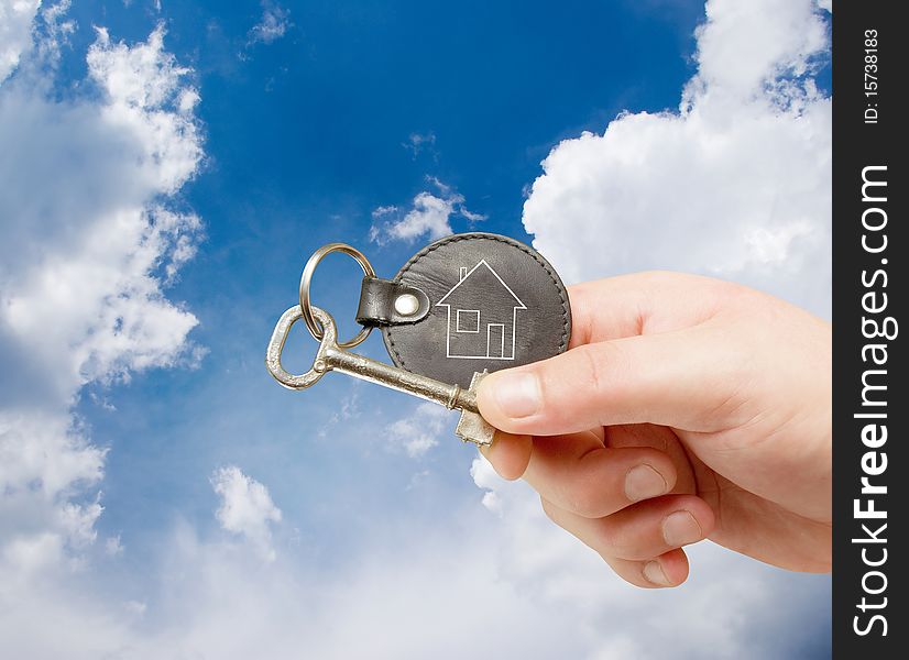 Keychain in human hand on sky background