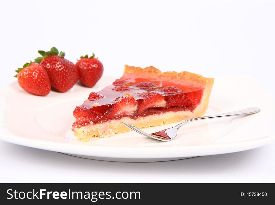 Piece of Strawberry Tart on a plate decorated with strawberries, and a fork