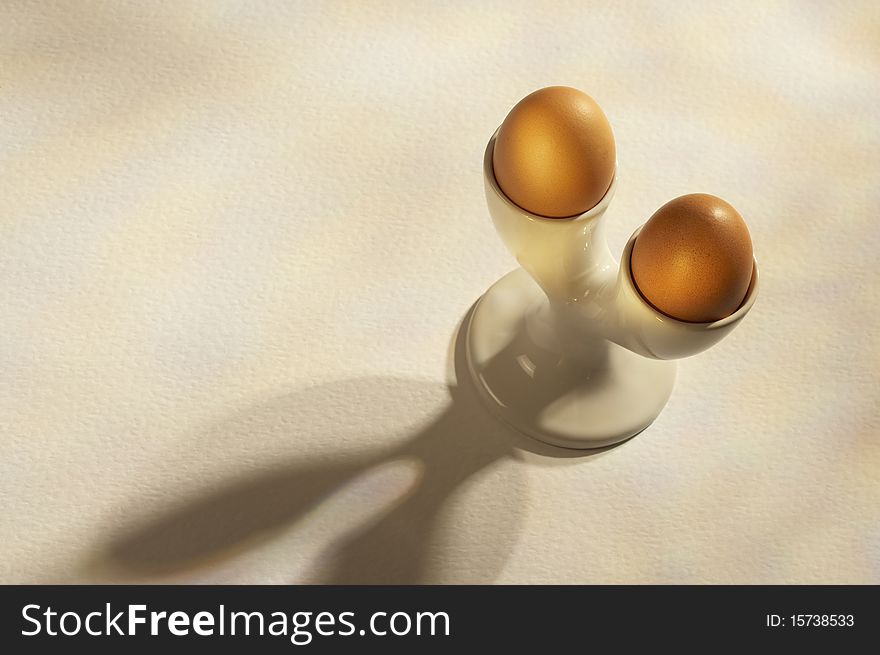 Two brown eggs in double white cup on white table. Two brown eggs in double white cup on white table