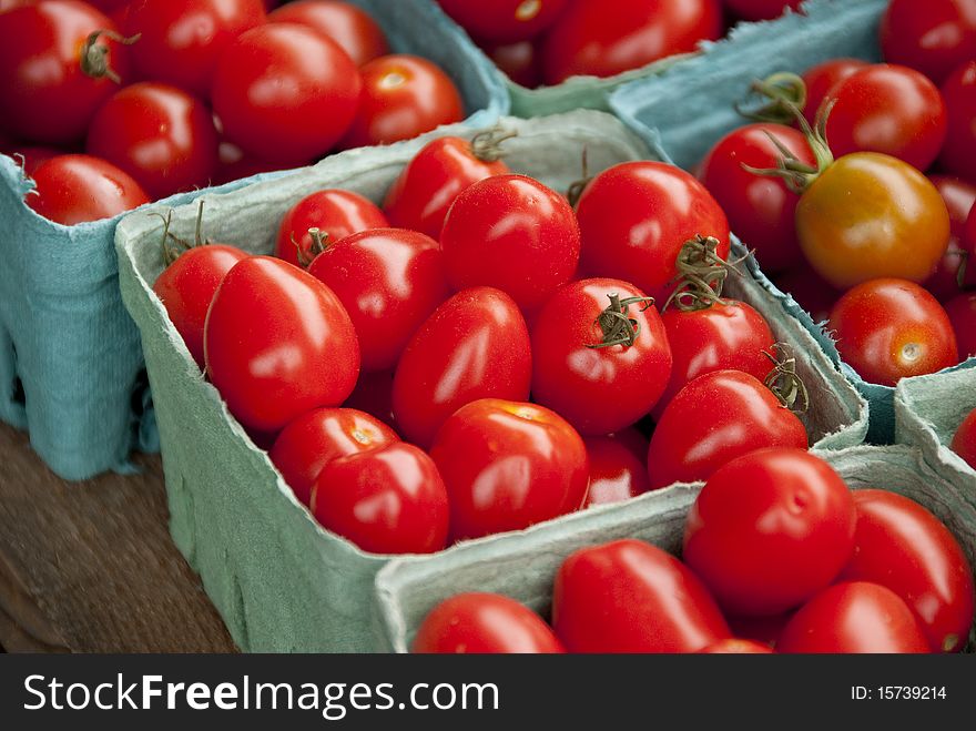 Various kinds of tomatoes in blue boxes on vegetable stand