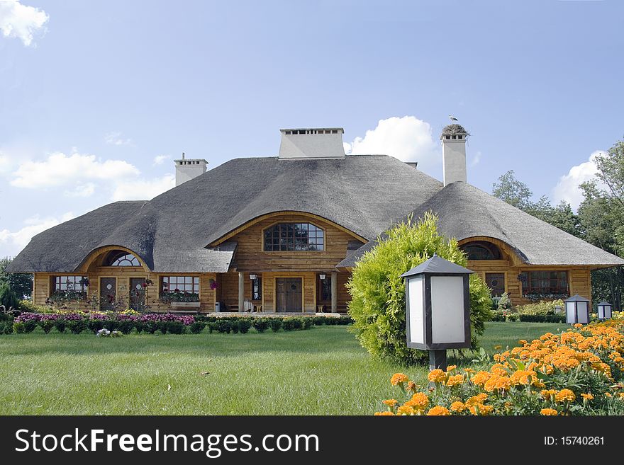 The house from a tree and straw with a stork on a roof. The house from a tree and straw with a stork on a roof