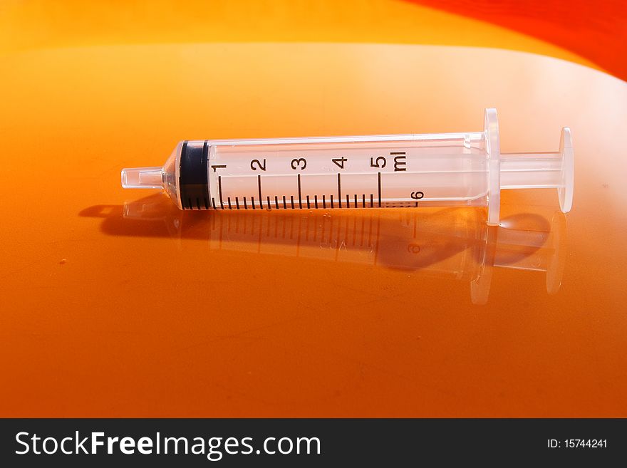 Syringe on water  orange background