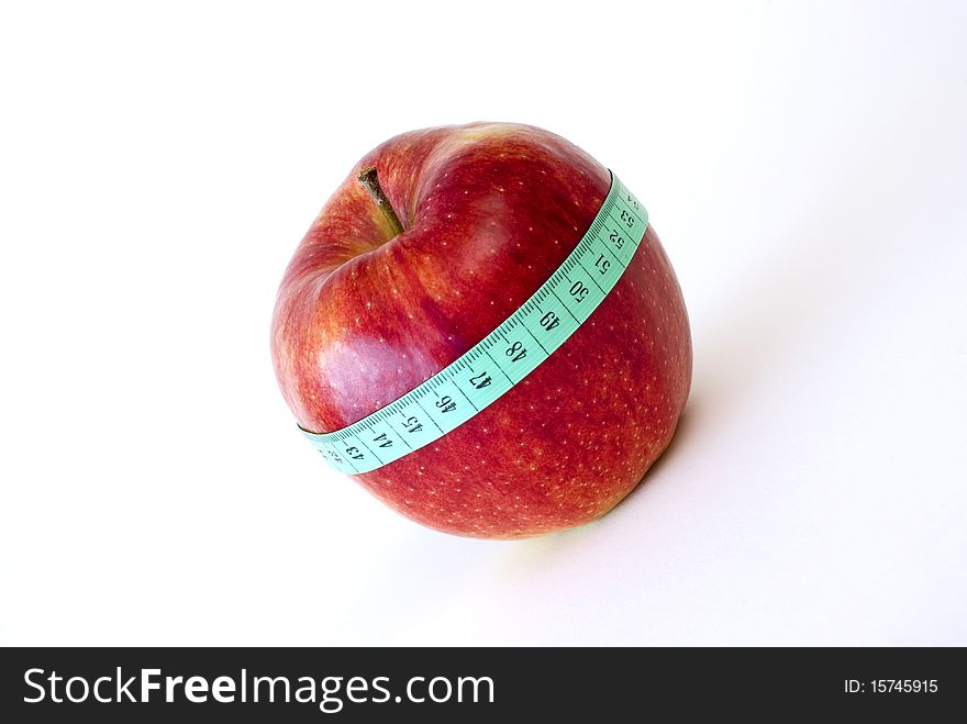 Fresh red apple wrapped up with the tape measure on the white background