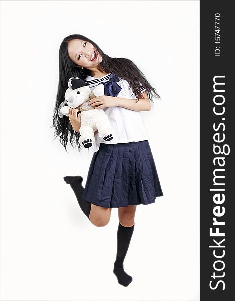 Female student in traditional uniform holding toy dog on white. Female student in traditional uniform holding toy dog on white.