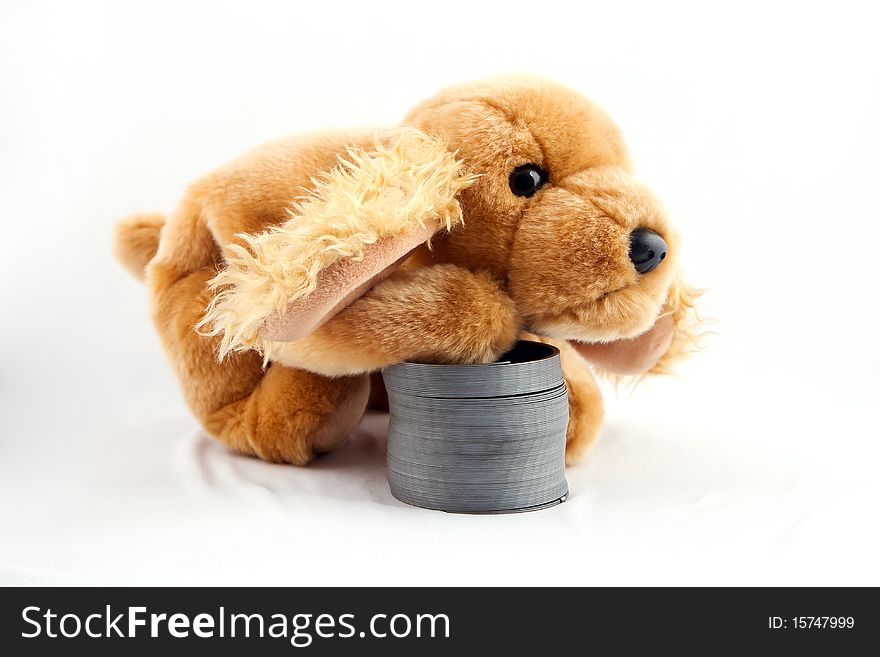 A tan cocker spanial puppy stuffed animal laying its paw on a old fashion slinky. A tan cocker spanial puppy stuffed animal laying its paw on a old fashion slinky