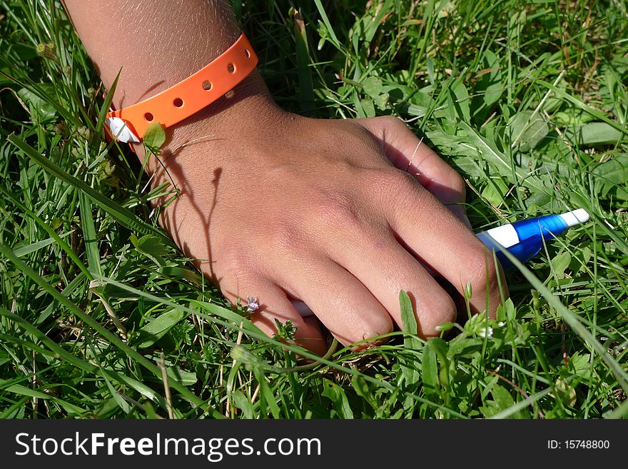 Young hand on grass with pen and platic wristband