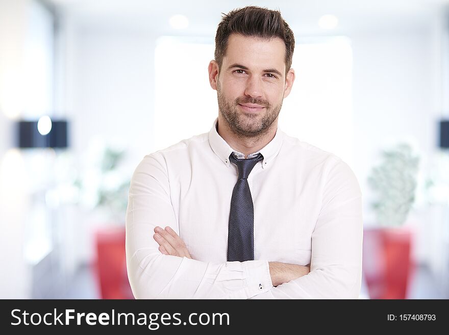 Portrait shot of smiling businessman wearing shirt and tie while standing in the office and smiling. Portrait shot of smiling businessman wearing shirt and tie while standing in the office and smiling