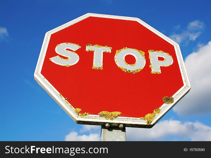 Close-up of an old red STOP sign with a blue sky background. Close-up of an old red STOP sign with a blue sky background.