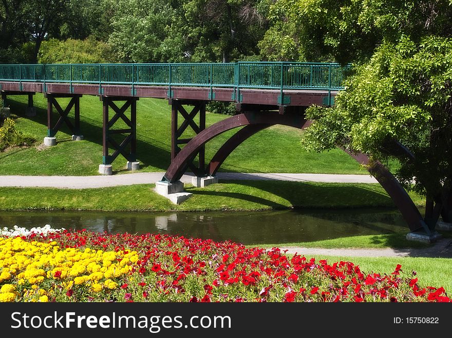 A brigde in the park with some red and yellow flowers. A brigde in the park with some red and yellow flowers