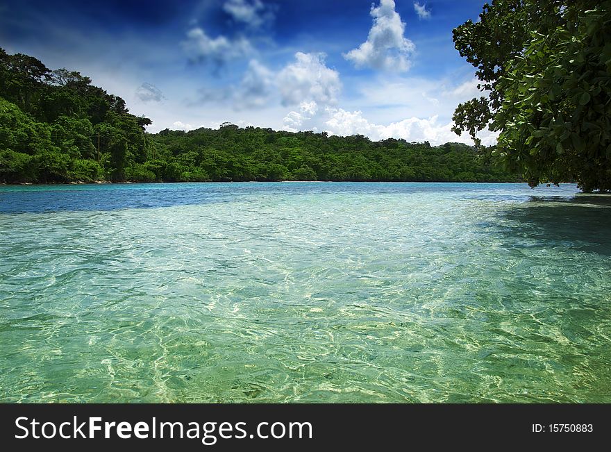 View of clear tropical waters with blue sky and lush green shoreline. View of clear tropical waters with blue sky and lush green shoreline