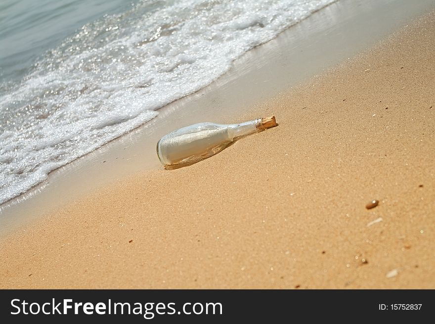 Letter in a bottle on beach with waves.